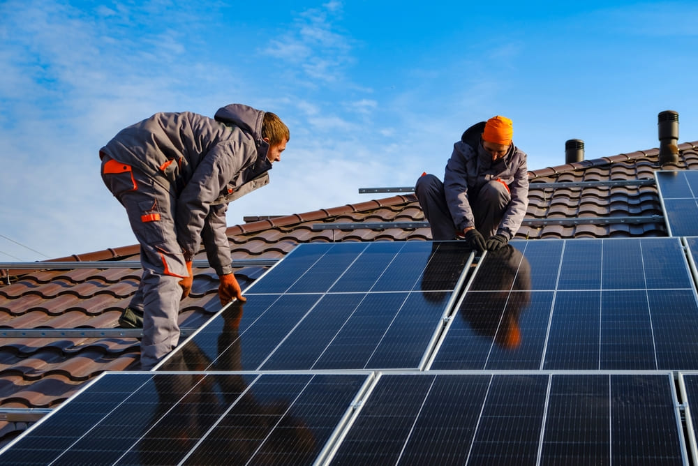 Installateurs en pleine pose de panneaux solaires sur une toiture inclinée