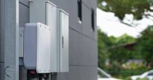 Batterie de stockage d'énergie solaire installée sur façade extérieure avec coffrets électriques et câblage