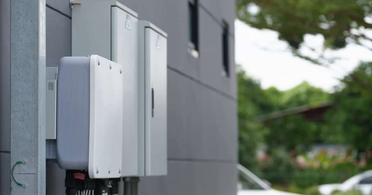 Batterie de stockage d'énergie solaire installée sur façade extérieure avec coffrets électriques et câblage