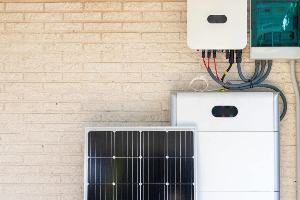 Techniciens professionnels installant des panneaux solaires photovoltaïques sur toiture inclinée pour système avec batterie