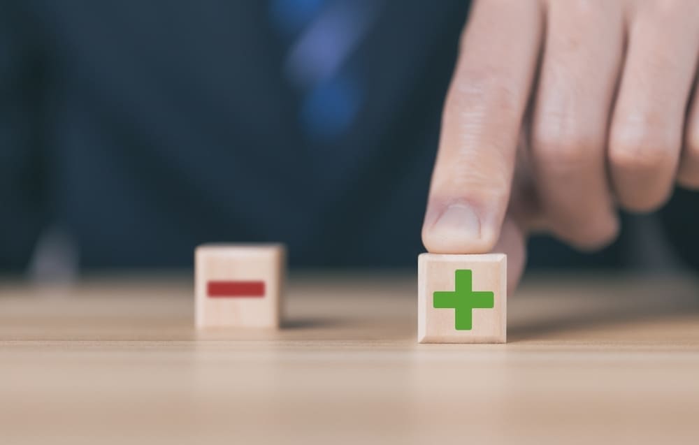 Main choisissant cube avec symbole plus vert représentant décision positive pour fournisseur énergie renouvelable