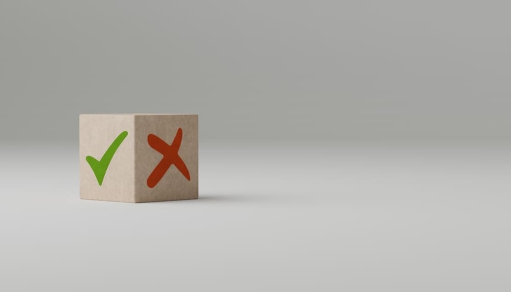 Cube en bois avec symboles coche verte et croix rouge illustrant avantages et inconvénients du choix fournisseur électricité
