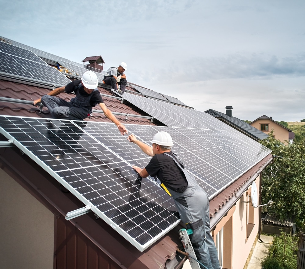 Équipe de techniciens professionnels installant des panneaux solaires photovoltaïques sur toiture résidentielle