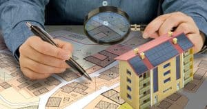 Professionnel analysant plan d'urbanisme PLU avec maquette de bâtiment équipé de panneaux solaires photovoltaïques
