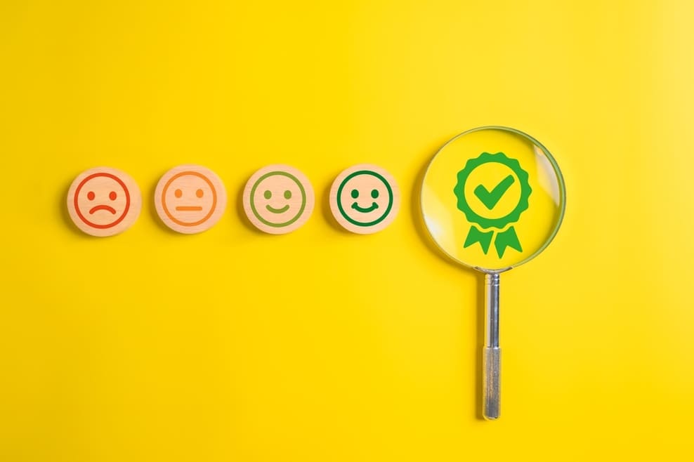 Échelle de satisfaction avec smileys et loupe sur badge de certification verte illustrant garantie de qualité et performance