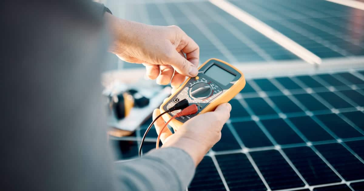 Main tenant un multimètre numérique pour mesurer la tension d'un panneau solaire photovoltaïque