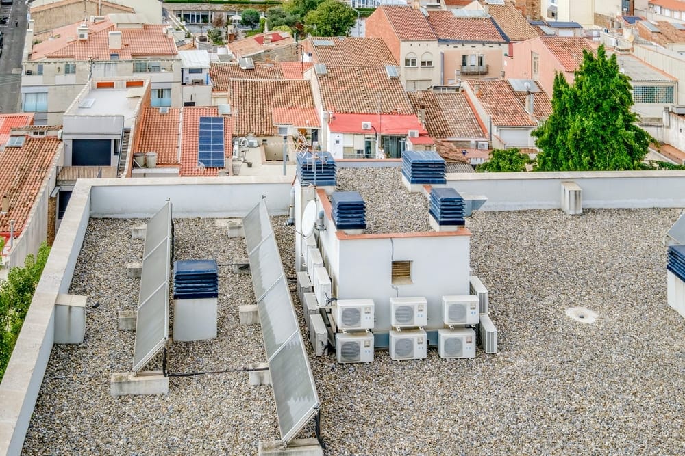 Installation de panneaux solaires lestés sur toit plat d'immeuble avec système de ballast en gravier
