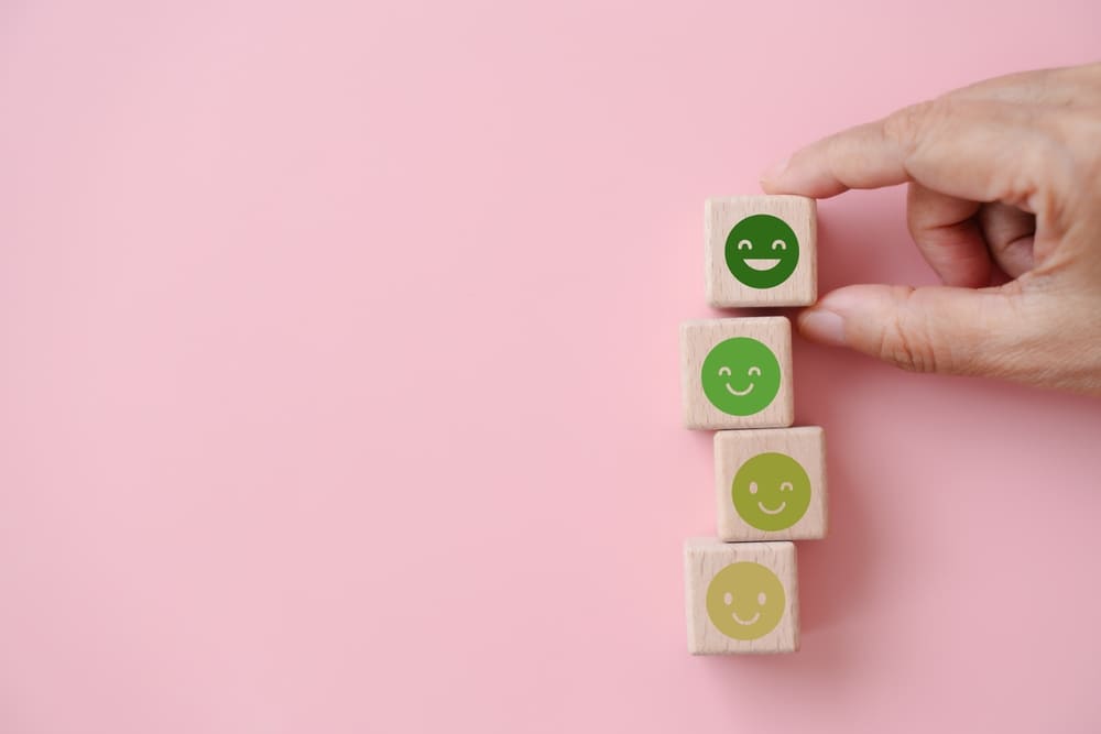 Main empilant cubes avec smileys verts représentant les avis positifs et satisfaction client de la marque Growatt