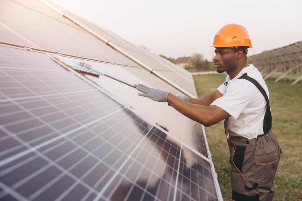 Technicien professionnel installant des panneaux solaires photovoltaïques en extérieur avec équipement de sécurité