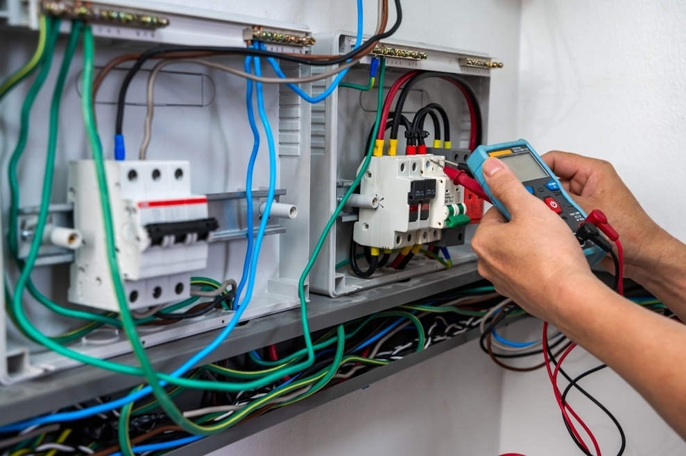 Main testant disjoncteur photovoltaïque avec multimètre dans tableau électrique pour installation solaire sécurisée