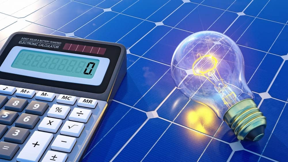 Calculatrice et ampoule allumée posées sur un panneau solaire illustrant la conversion de l'énergie par l'onduleur