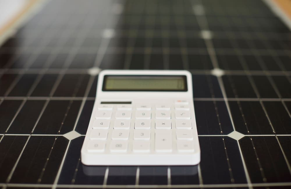 Calculatrice posée sur un panneau solaire pour calculer le rendement et comparer les performances des onduleurs