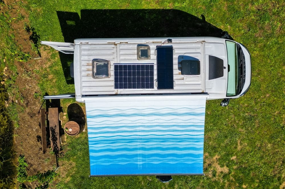 Vue aérienne d'un camping-car avec panneau solaire photovoltaïque sur le toit et store déployé en bivouac