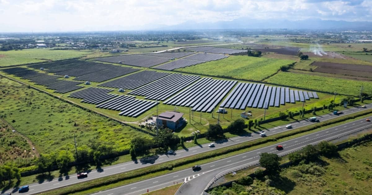 Vue aérienne d'une centrale solaire au sol avec plusieurs rangées de panneaux photovoltaïques installés sur terrain agricole