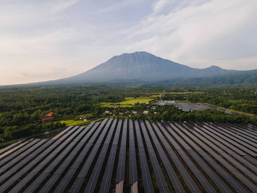 Champ photovoltaïque de grande puissance s'étendant sur plusieurs hectares avec montagne en arrière-plan