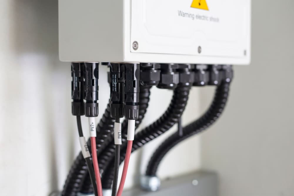 Connecteurs MC4 et câbles raccordés aux entrées PV d'un onduleur solaire pour installation photovoltaïque