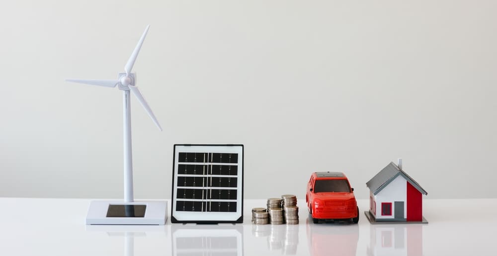 Miniatures illustrant les énergies renouvelables avec éolienne, panneau solaire, pièces de monnaie, voiture électrique et maison