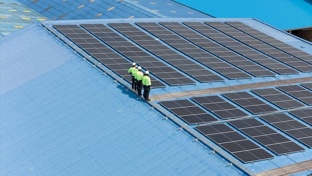 Techniciens installant des panneaux solaires sur une toiture industrielle pour une centrale photovoltaïque