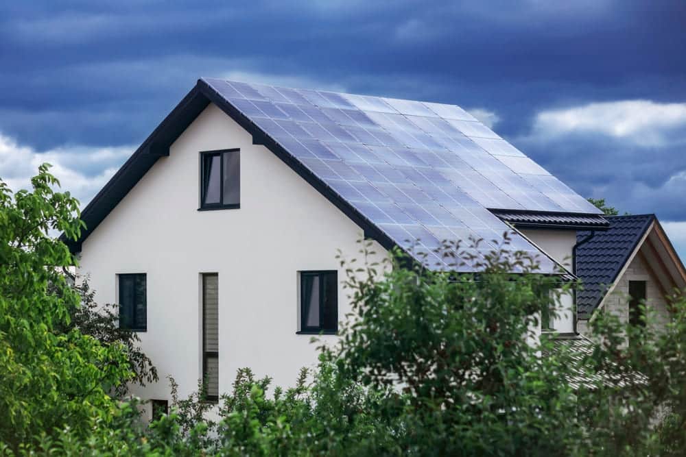 Maison avec installation solaire photovoltaïque sur toiture sous un ciel orageux menaçant