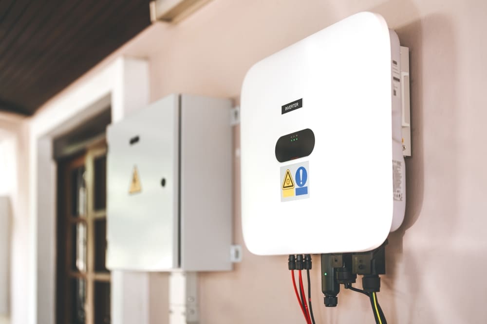 Onduleur photovoltaïque blanc avec voyants LED installé à côté du tableau électrique de protection