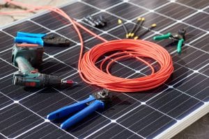 Outils nécessaires à l'installation d'un micro-onduleur : perceuse, pinces, câbles et connecteurs MC4 sur panneau solaire