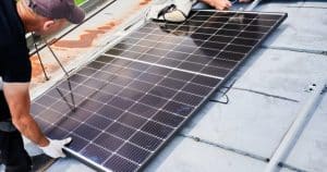 Installateurs posant un panneau solaire photovoltaïque sur une toiture plate pour production d'électricité
