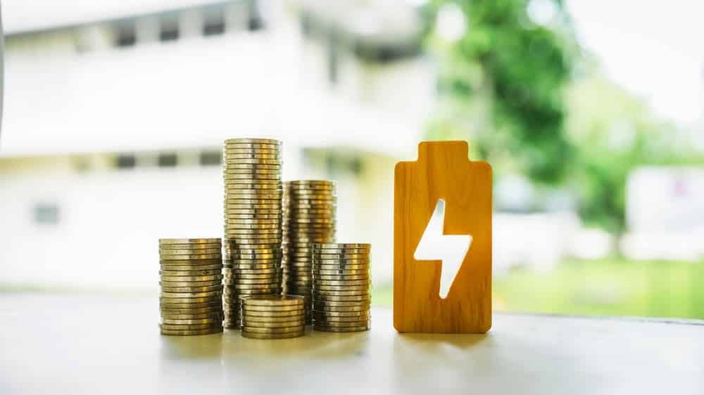 Piles de pièces de monnaie et symbole de batterie illustrant les économies réalisées avec un onduleur hybride et le stockage d'énergie