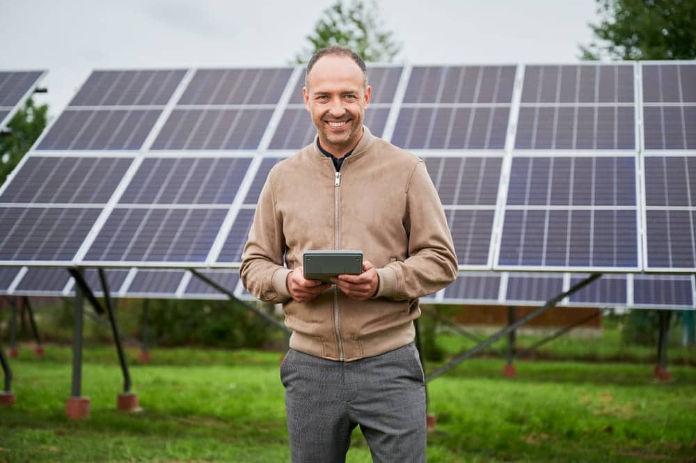 Propriétaire consultant sa tablette devant son installation de panneaux solaires pour suivre sa production d'électricité