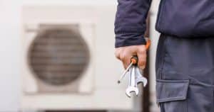 Technicien équipé d'outils prêt à intervenir sur une pompe à chaleur pour vérifier son dimensionnement