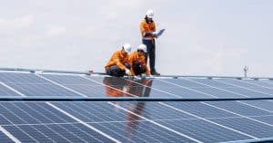 Équipe de techniciens en tenue de sécurité vérifiant le bon fonctionnement d'une installation de panneaux solaires sur toiture