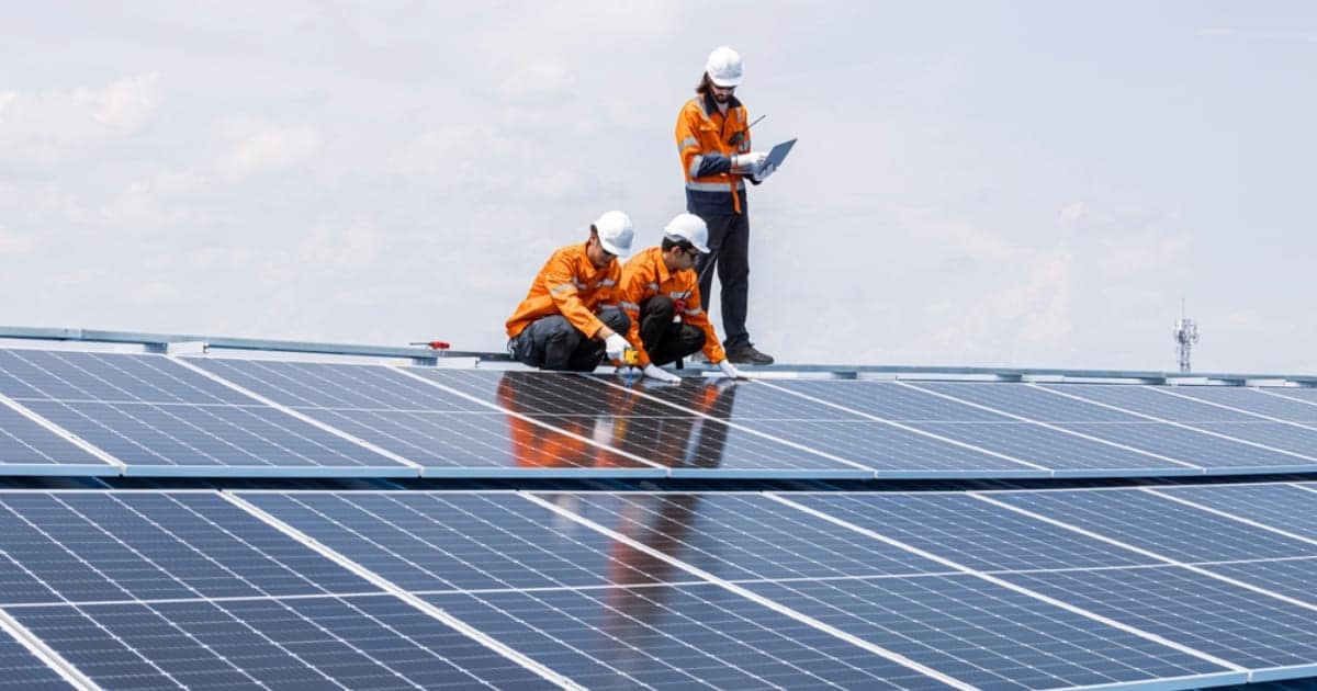 Équipe de techniciens en tenue de sécurité vérifiant le bon fonctionnement d'une installation de panneaux solaires sur toiture