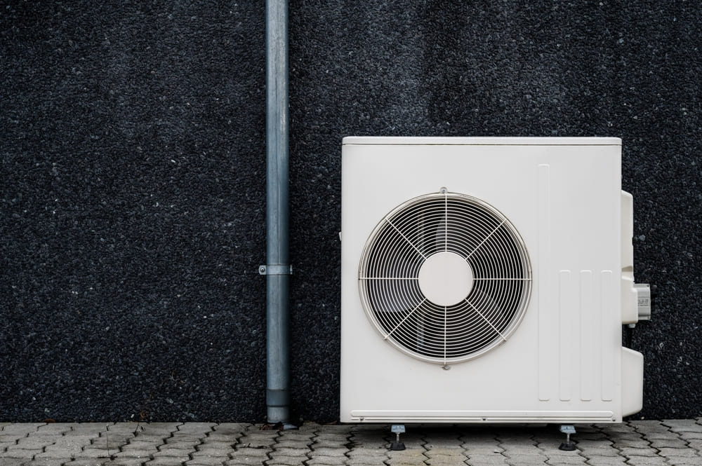 Unité extérieure de pompe à chaleur air-eau installée contre un mur de maison individuelle