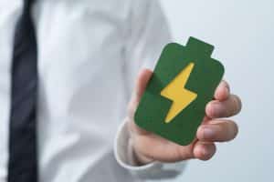 Main tenant une icône de batterie verte symbolisant le stockage d'énergie solaire et le choix de la bonne capacité