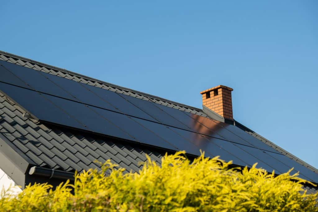  Maison moderne équipée de panneaux solaires noirs intégrés au toit pour autoconsommation avec batterie physique