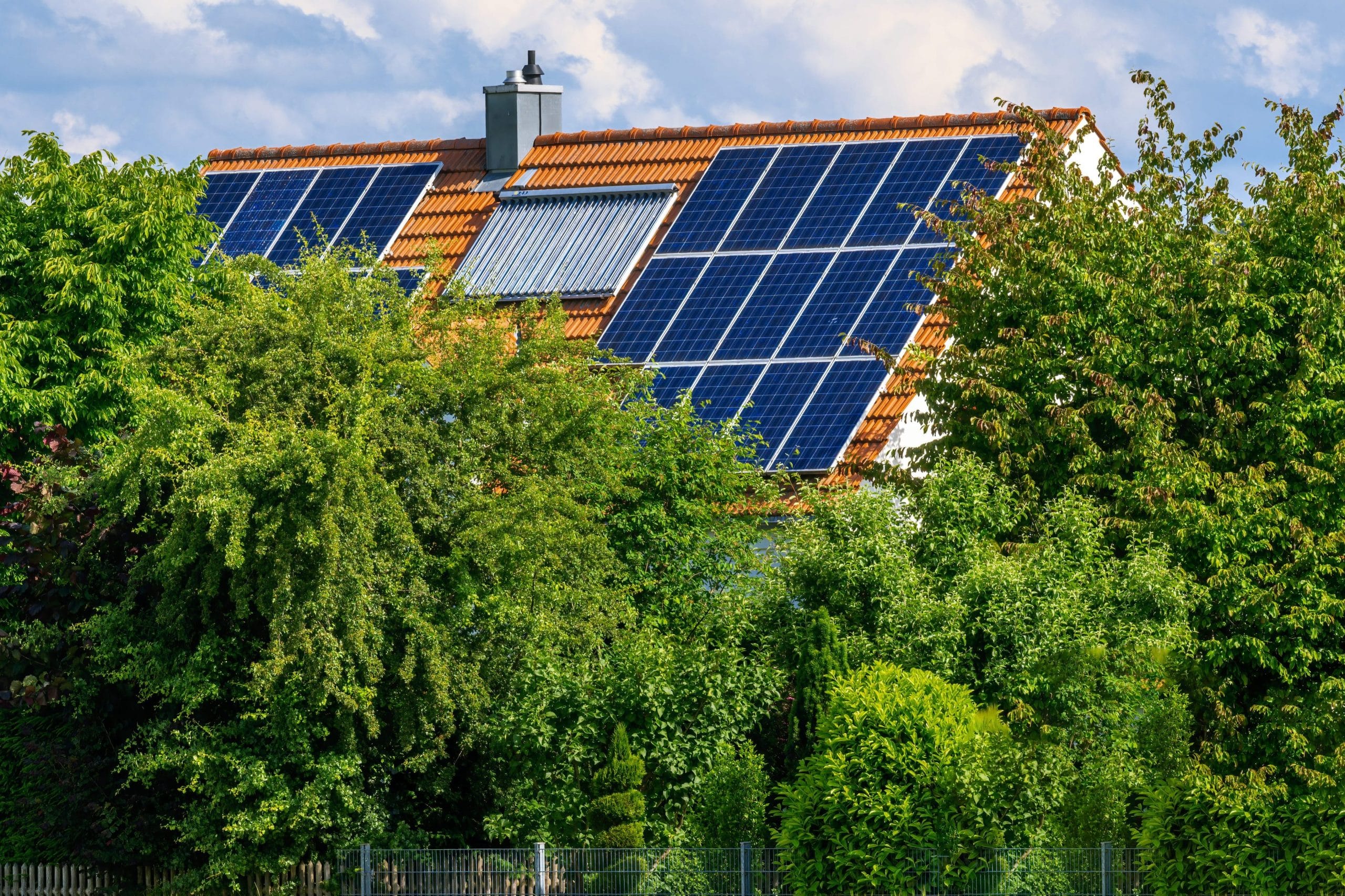 Maison individuelle équipée de panneaux solaires photovoltaïques et thermiques sur toiture en tuiles pour maximiser la rentabilité
