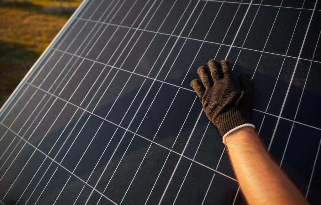  Main gantée nettoyant la surface d'un panneau solaire pour optimiser la production d'énergie