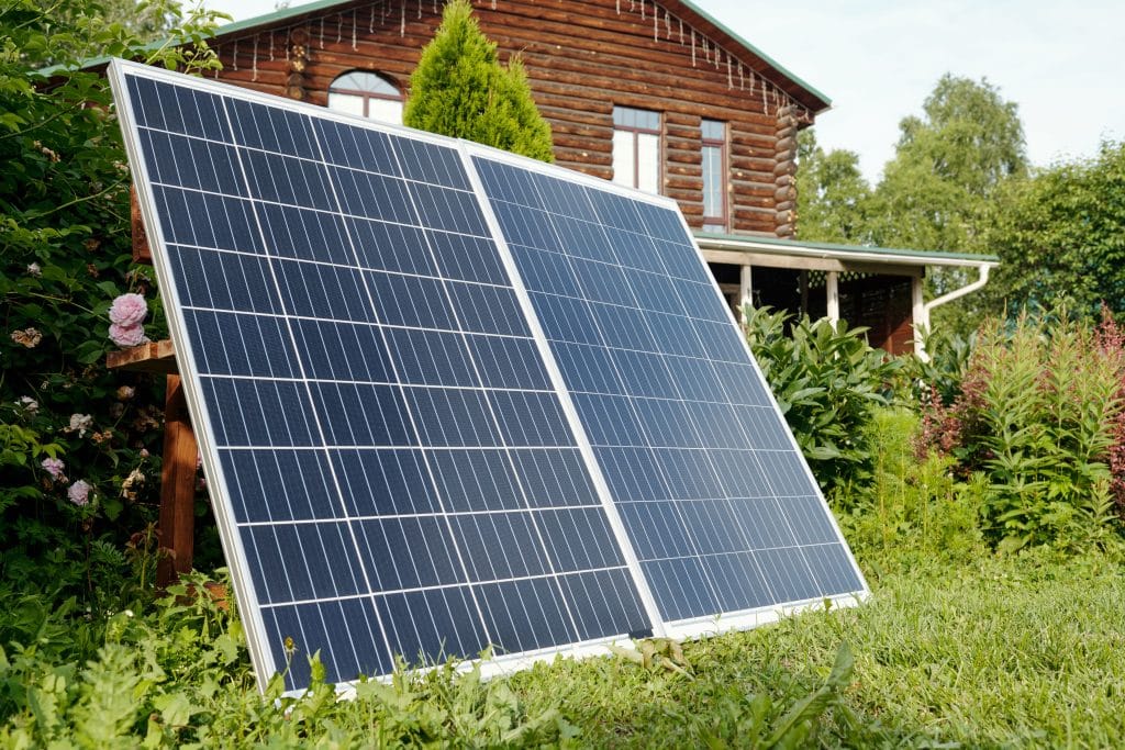 Deux panneaux solaires installés dans le jardin d'une maison en bois pour une production en autoconsommation avec batterie de stockage