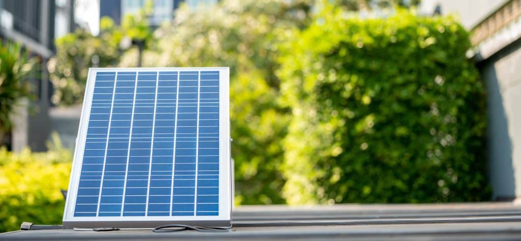 Petit panneau solaire portable polycristallin posé en extérieur dans un environnement urbain végétalisé