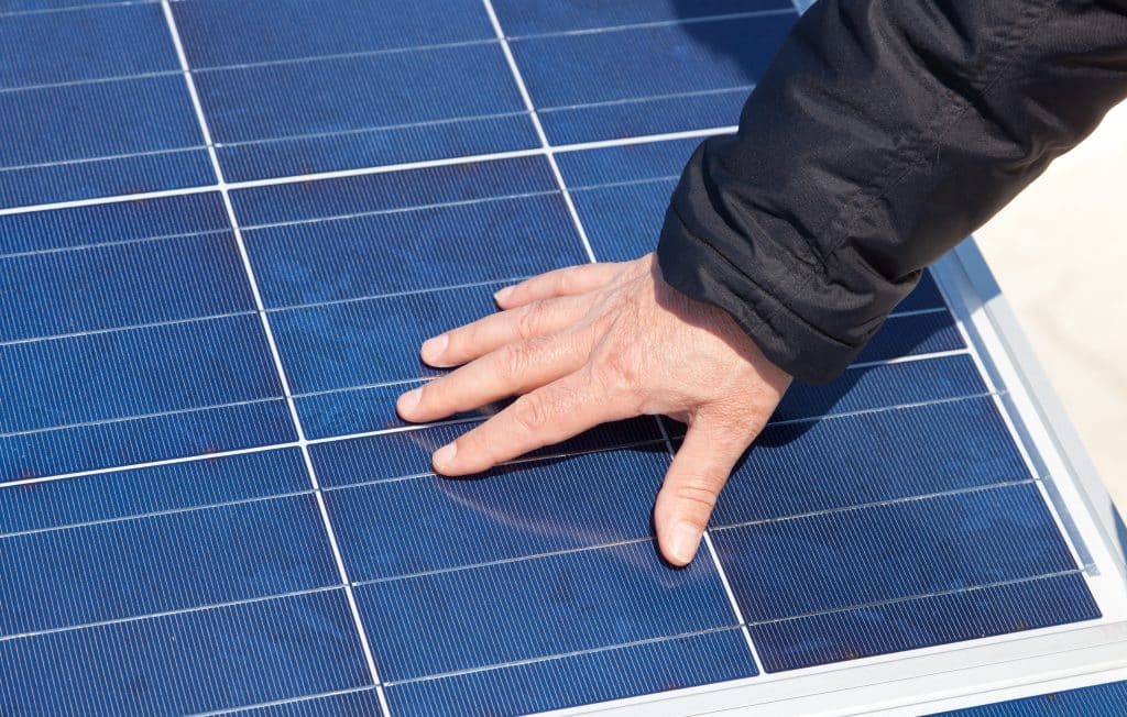 Main posée sur un panneau solaire polycristallin pour vérifier la qualité avant achat chez Castorama