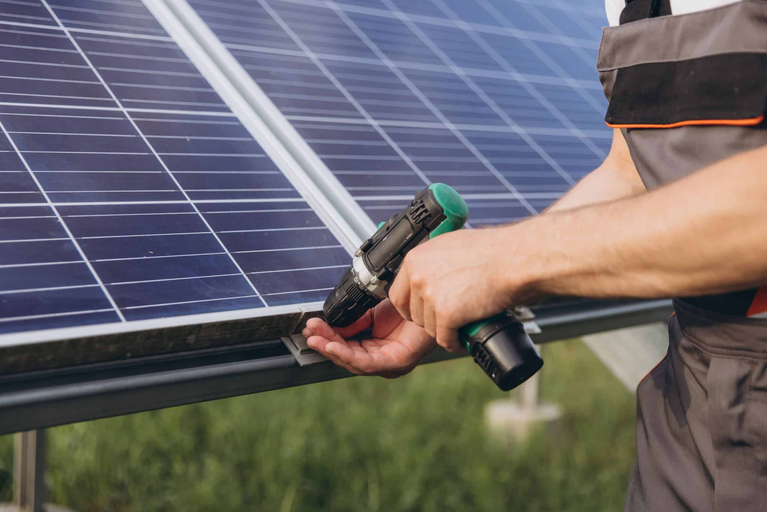 Technicien fixant un panneau solaire sur sa structure de support avec une visseuse pour une installation plug and play