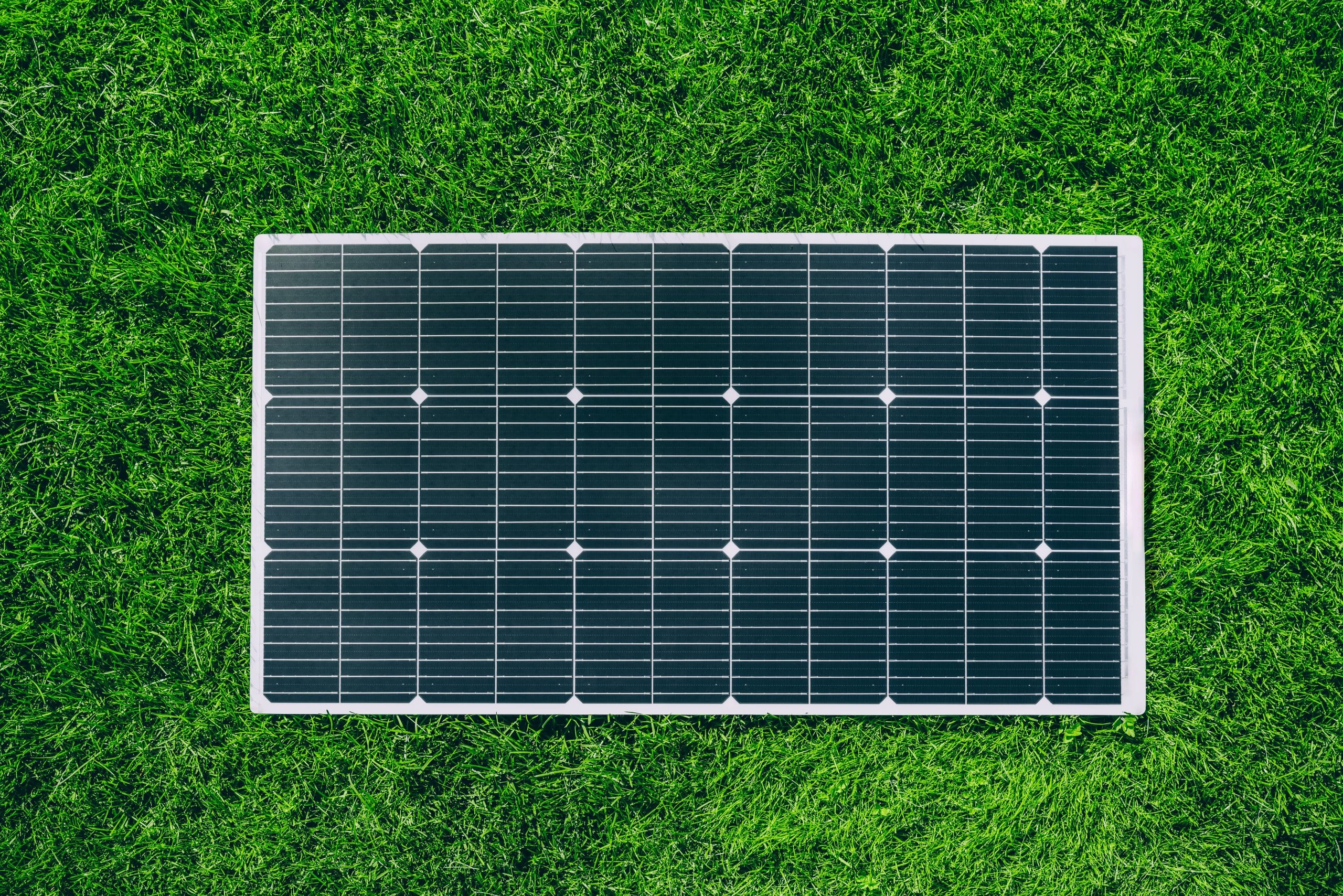 Vue de dessus d'un panneau solaire posé sur une pelouse verte idéal pour un kit solaire plug and play facile à installer