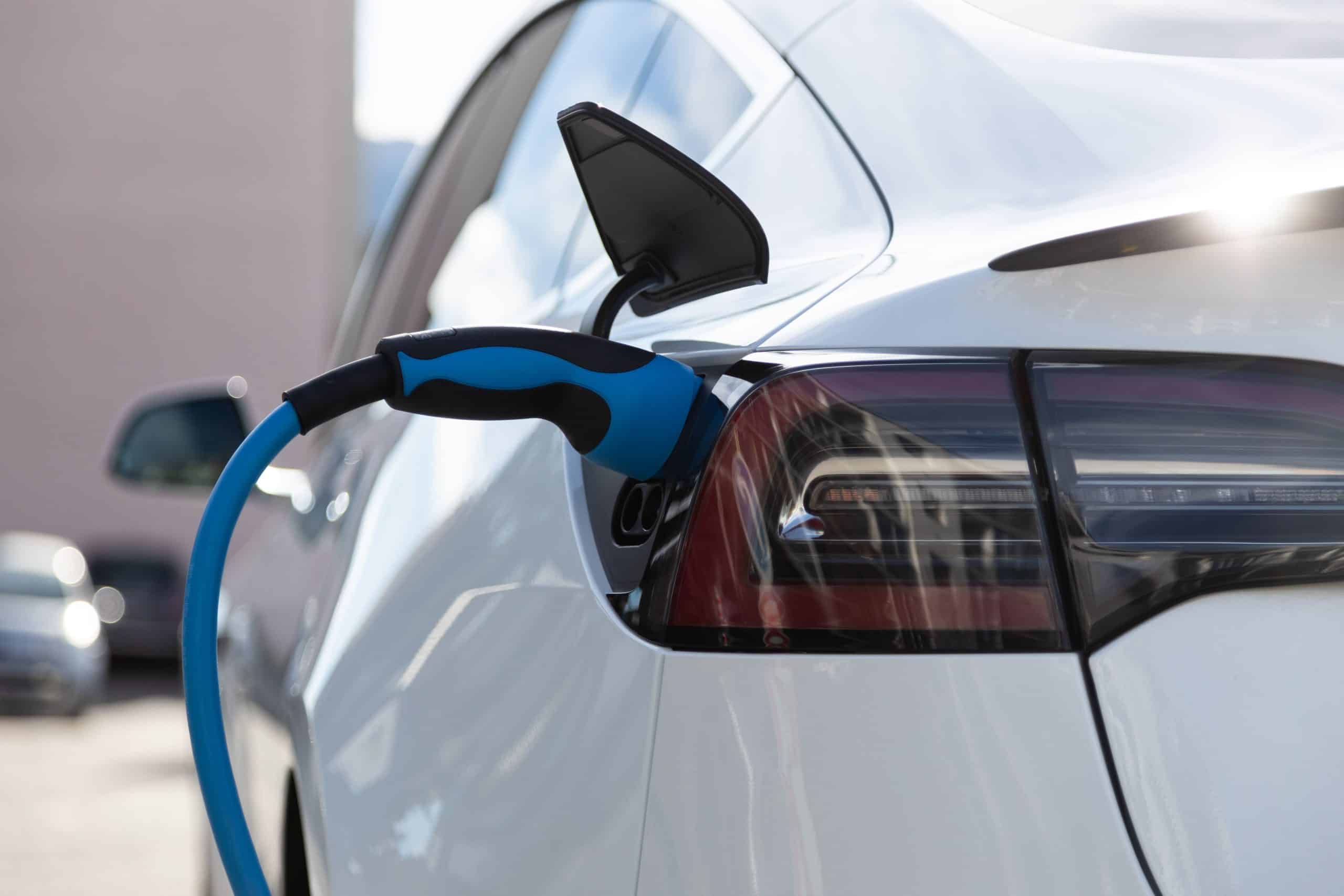 Voiture électrique branchée à une borne de recharge avec câble bleu pour la recharge à domicile ou en station