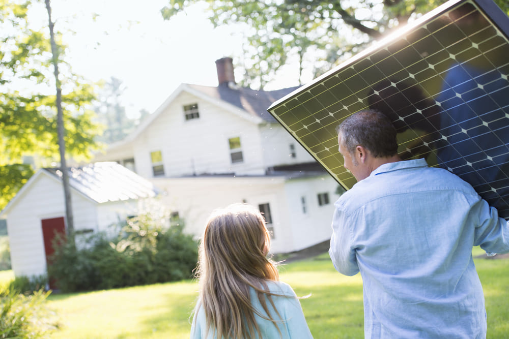 Un homme et une fille transportant un panneau solaire